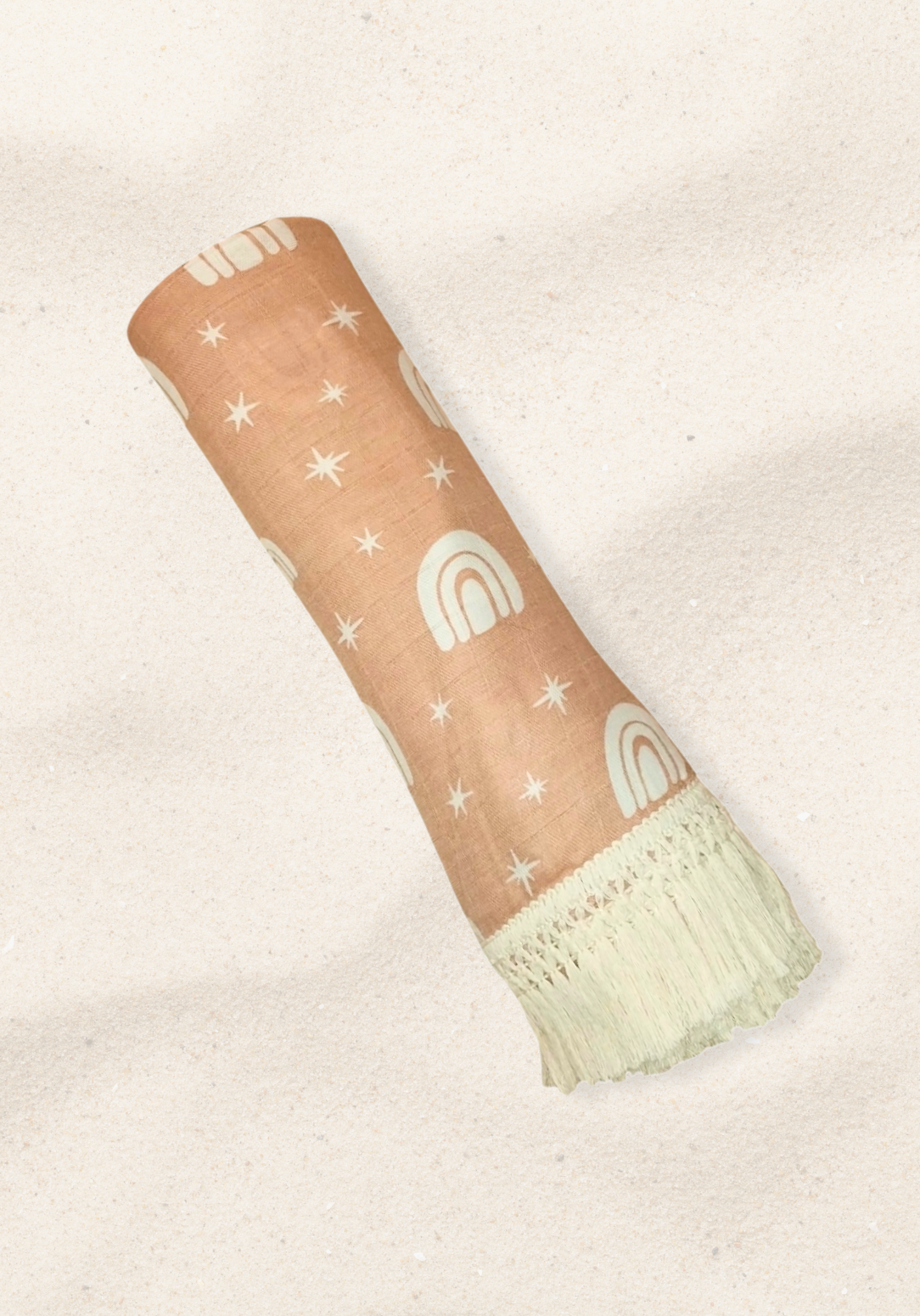 Peach baby blanket with white rainbow and star patterns, edged with cream fringe. Perfect for cozy snuggles.