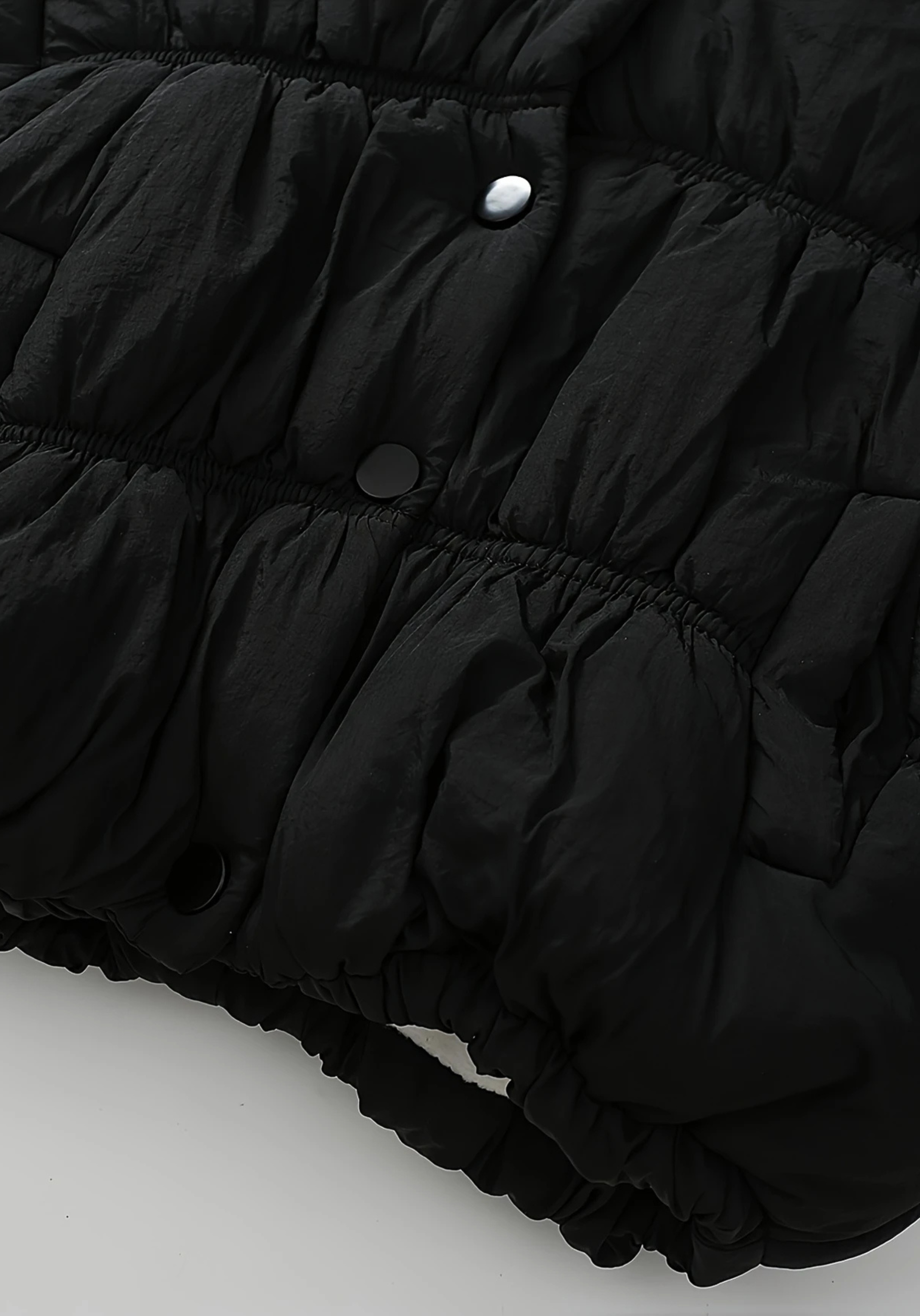 Close up view of toddler black puffer jacket with ruched detailing and high collar