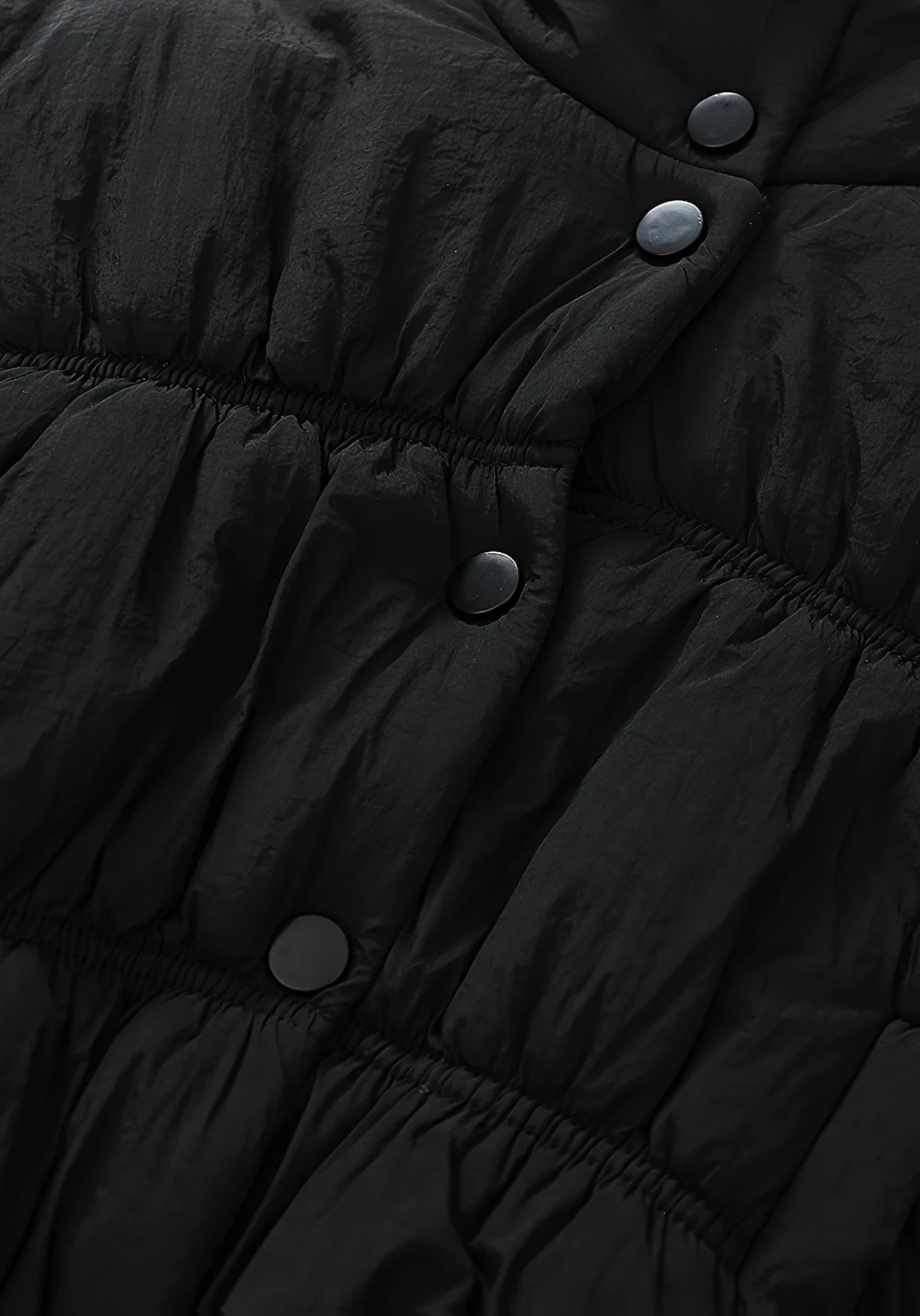 Close up view of toddler black puffer jacket with ruched detailing and high collar