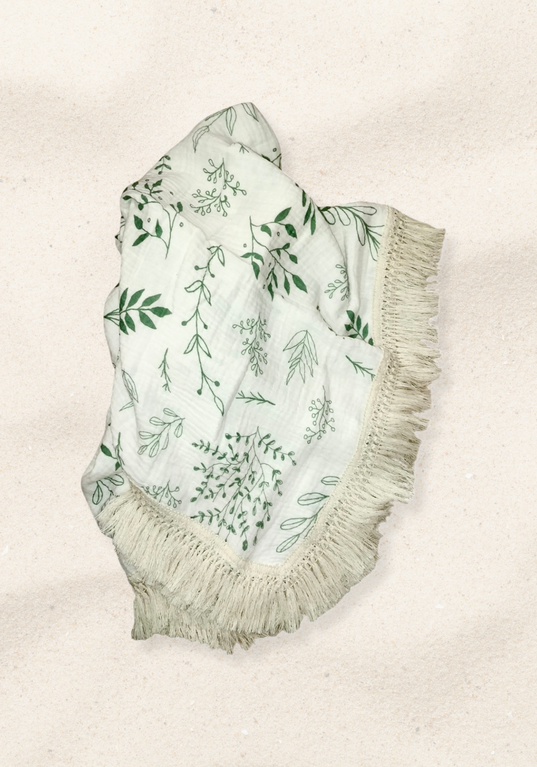White cotton baby blanket with green botanical leaf print and boho-inspired fringe border. Naturally breathable.