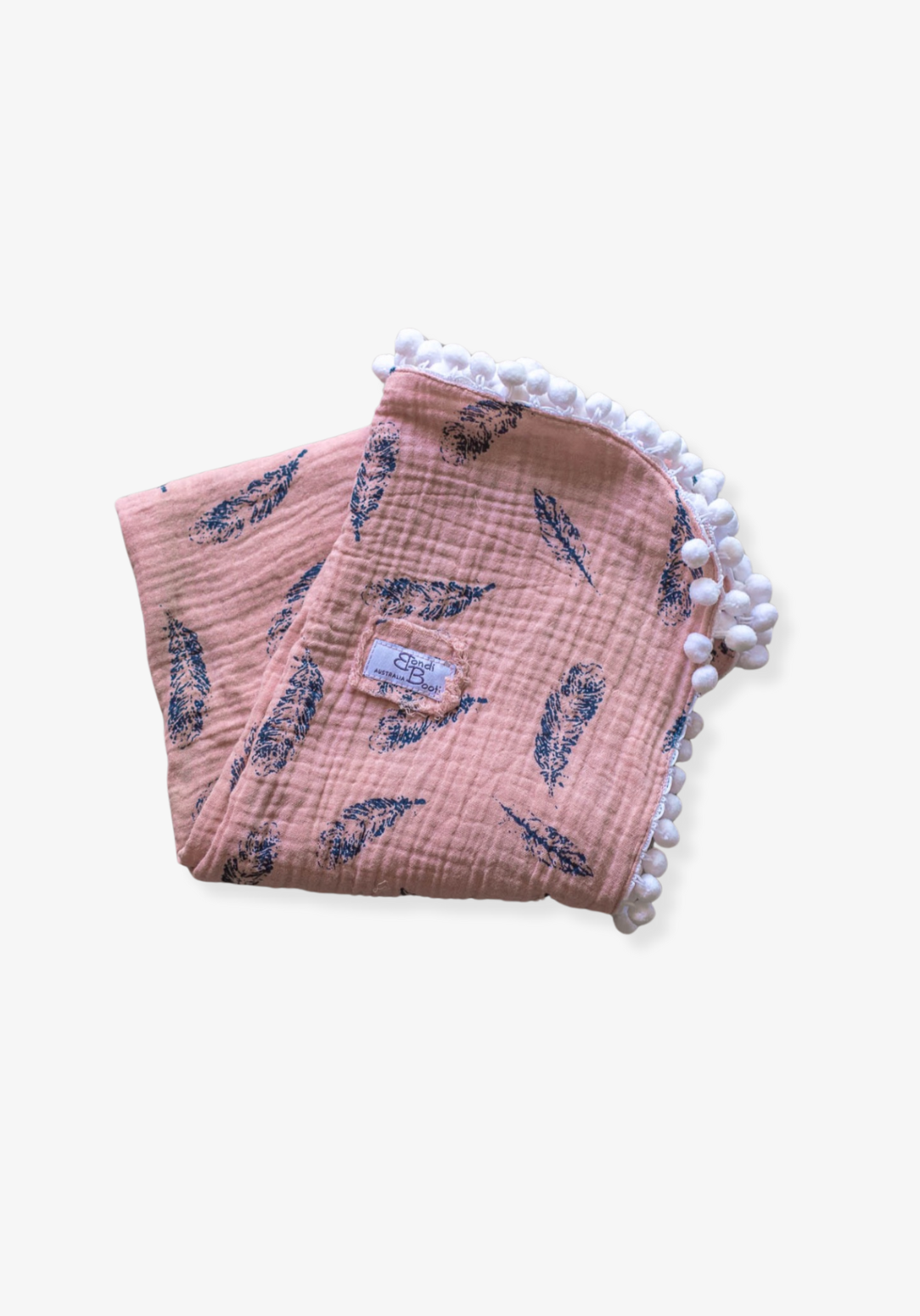 Dusty pink organic cotton baby blanket with navy feather print and white pom-pom trim, folded neatly with a visible Bondi Booti label.