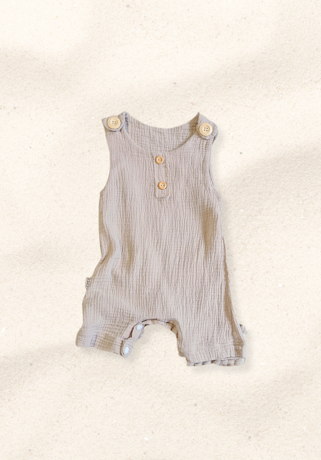 Beige organic cotton baby overall onesie with wooden button straps and soft elastic leg openings