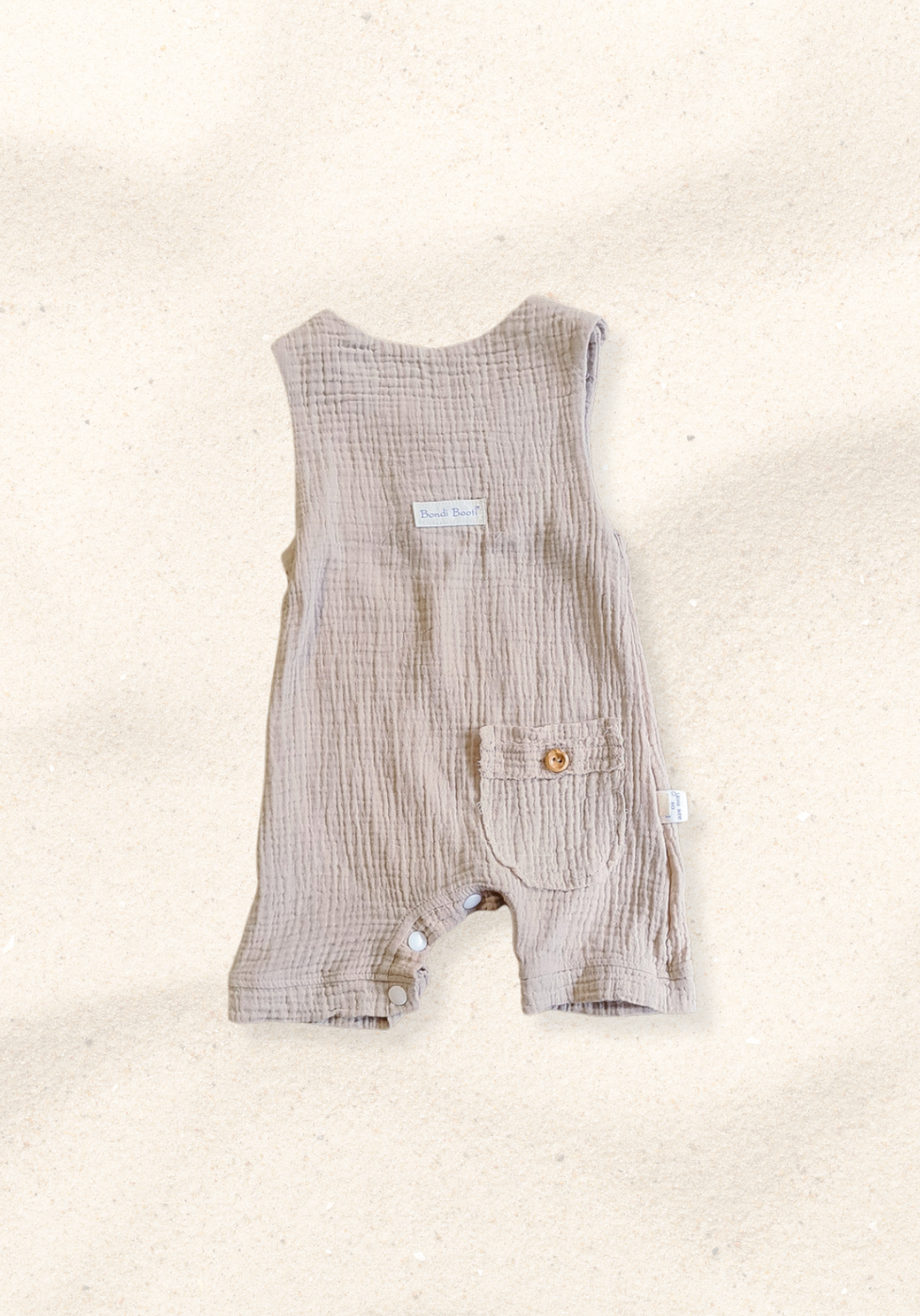 Beige organic cotton baby overall onesie with wooden button straps and soft elastic leg openings