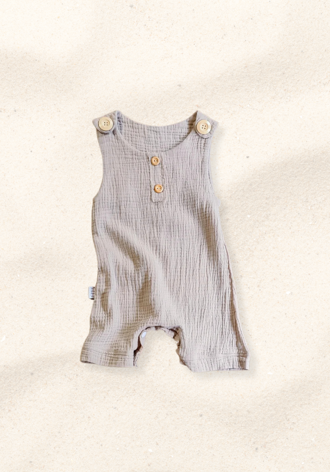 Beige organic cotton baby overall onesie with wooden button straps and soft elastic leg openings