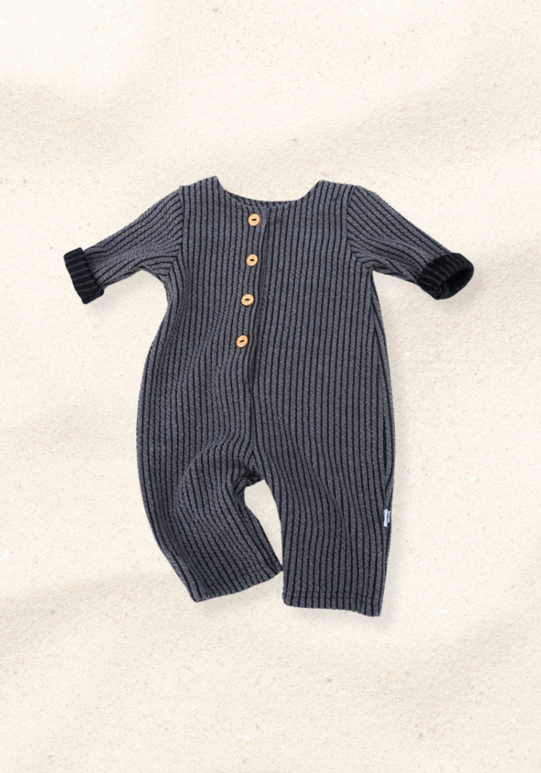 Long oversized baby onesie in charcoal ribbed fabric with front wooden button closure and folded sleeves