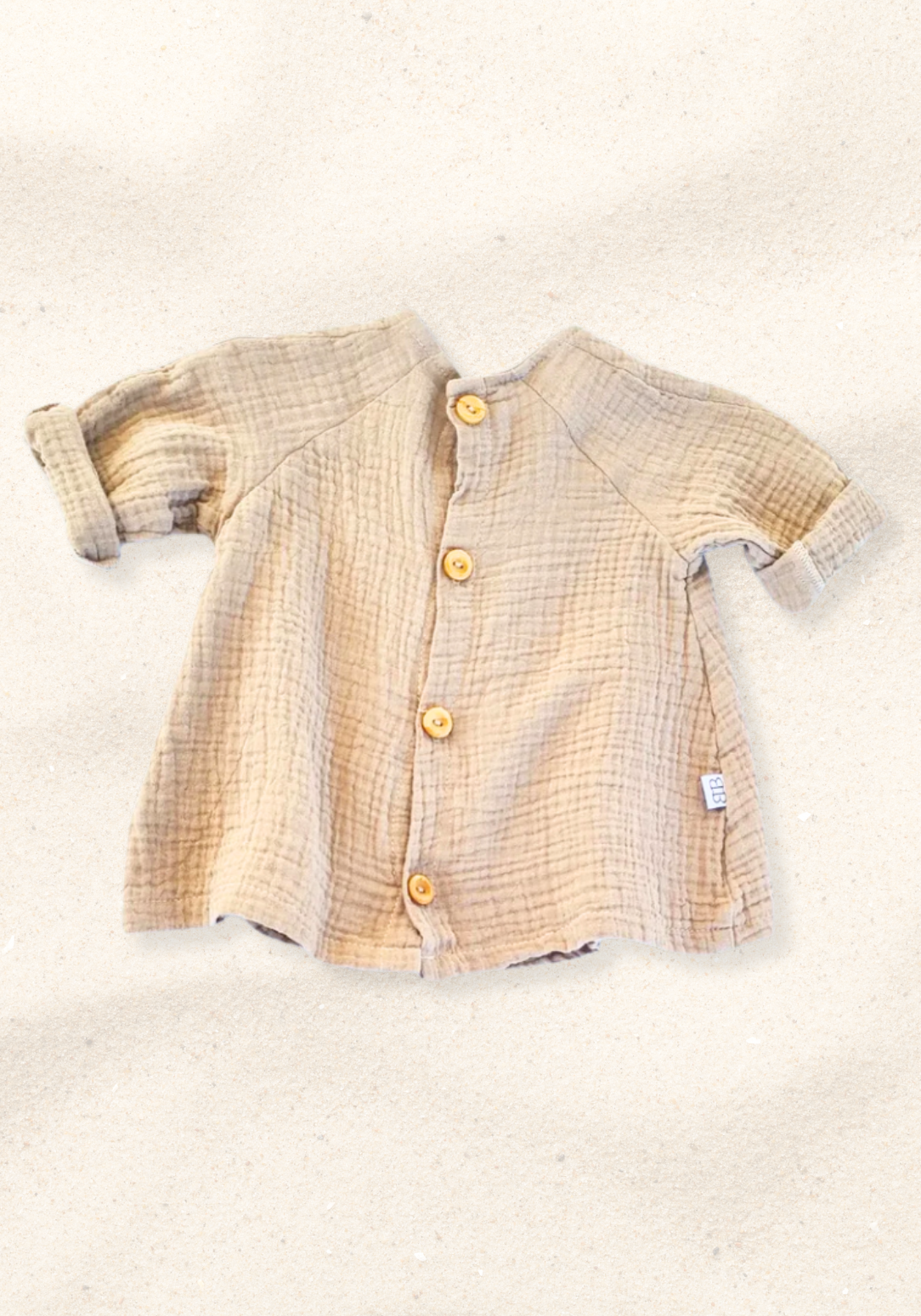 Mocha-colored cotton boho baby dress with embroidered hem, displayed on a sand background for a neutral look