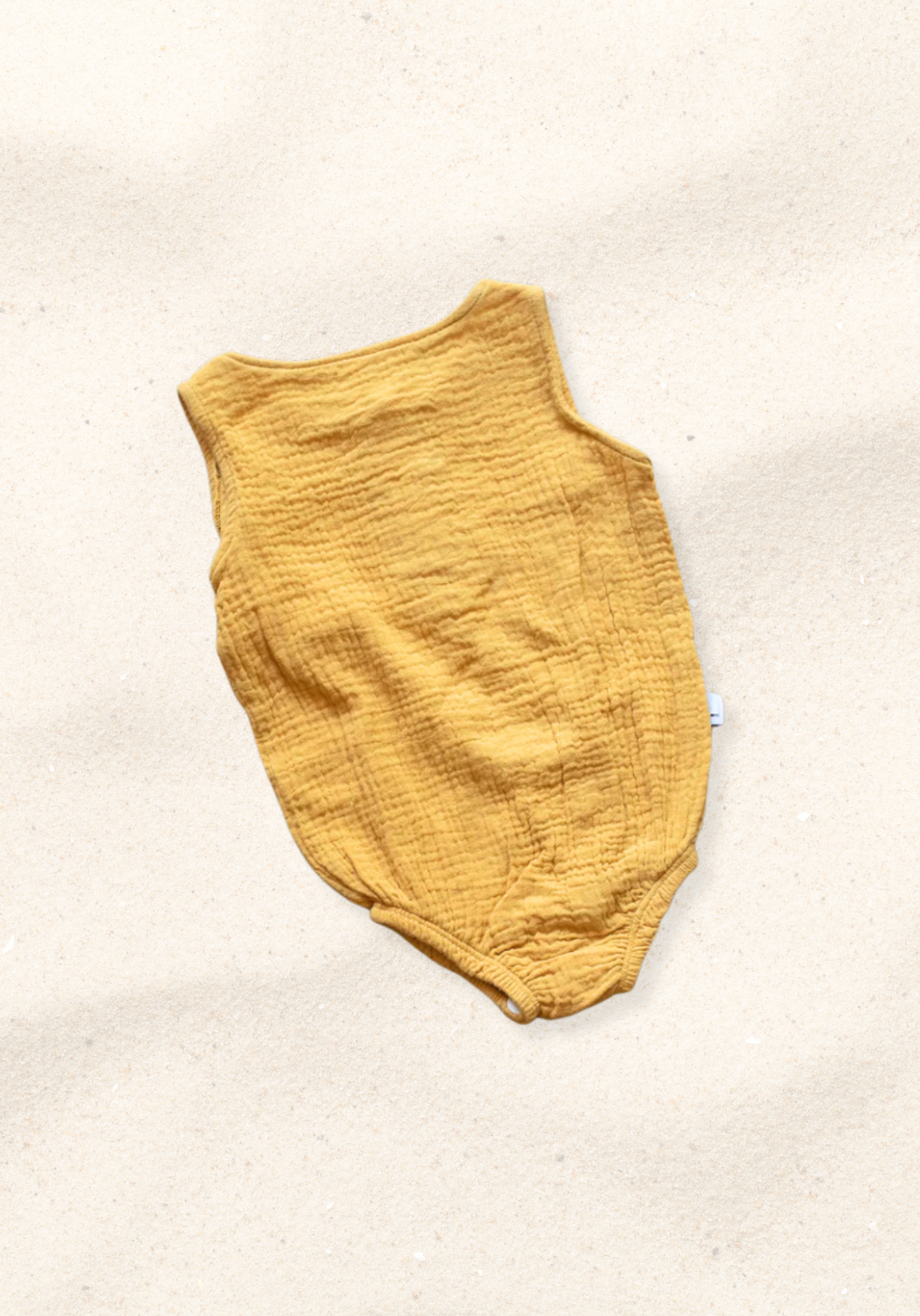 Mustard short sleeve organic cotton baby romper with three snap buttons at the bottom and elasticised leg bands