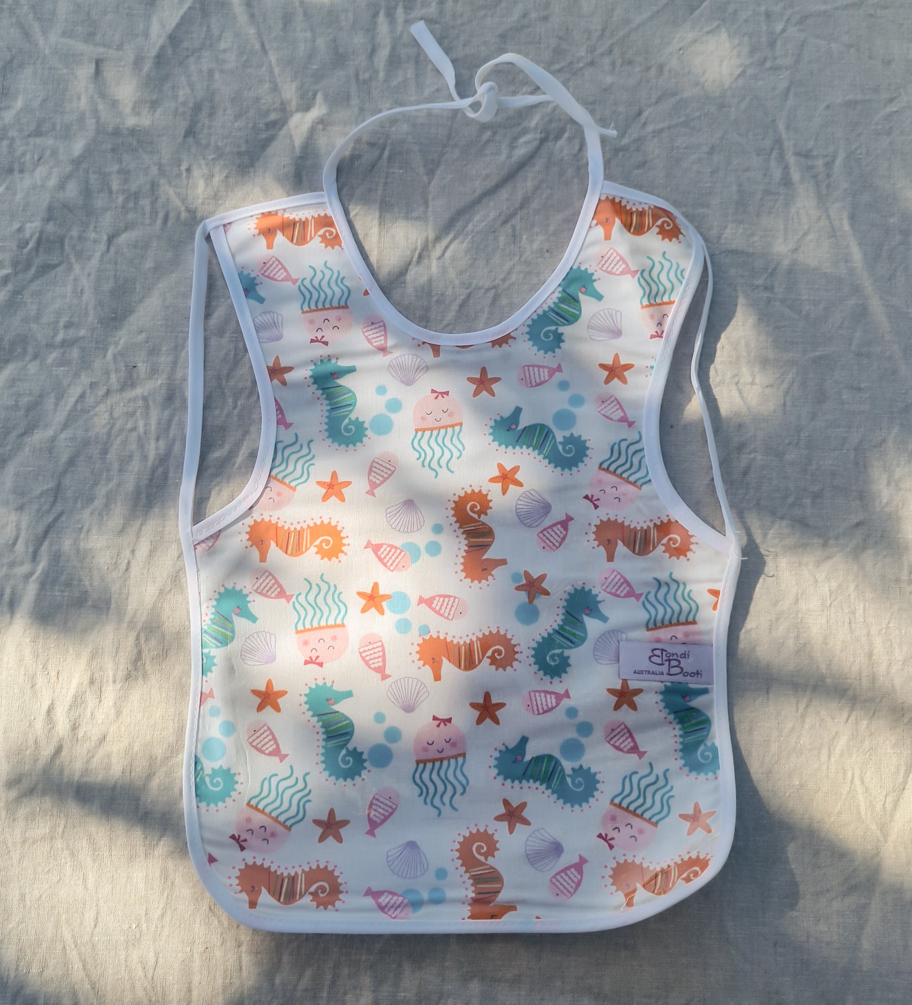 Laminated baby bib with seahorse and seashells design